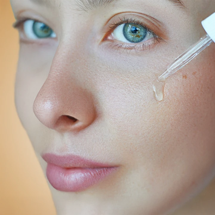 li-woman-applying-facial-serum-dropper-skincare-routine.jpg